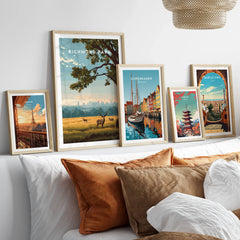 Framed travel posters of Richmond Park, Paris, Copenhagen, Tokyo, and Barcelona above a bed