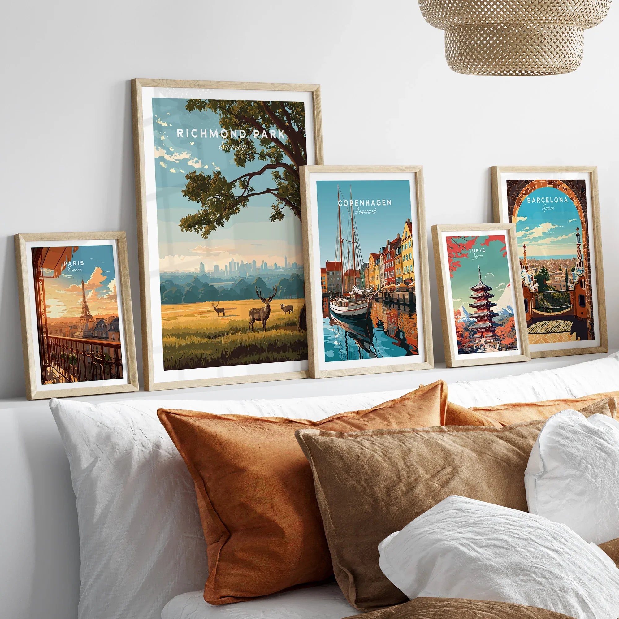 Framed travel posters of Richmond Park, Paris, Copenhagen, Tokyo, and Barcelona above a bed