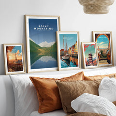 Framed travel art prints of Rocky Mountains, Paris, Copenhagen, Tokyo, and Barcelona above bed