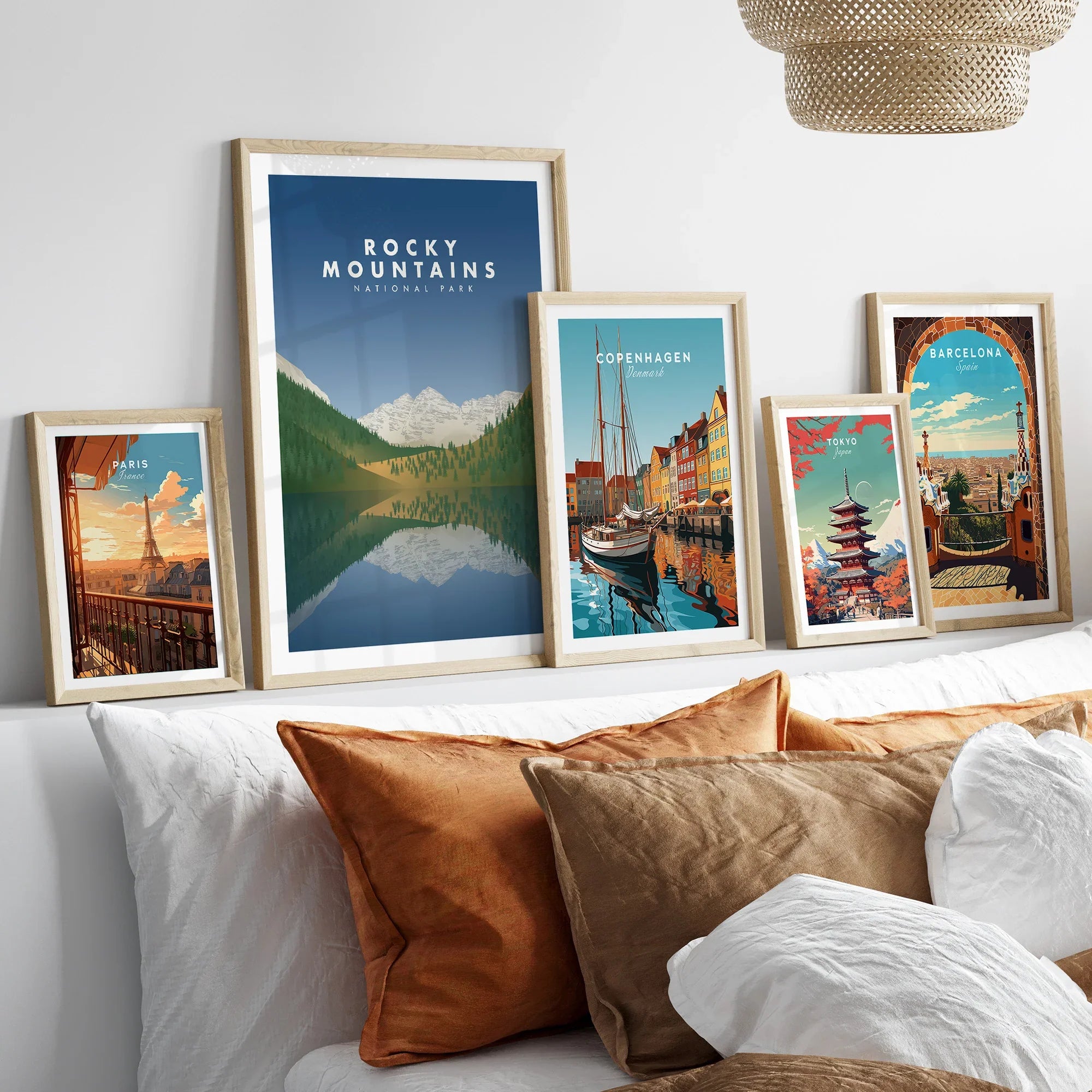 Framed travel art prints of Rocky Mountains, Paris, Copenhagen, Tokyo, and Barcelona above bed