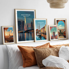 Set of five framed travel art prints with city skylines above a bed, natural wood frames