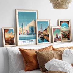 Set of five framed travel posters with city skylines above a bed with neutral pillows.