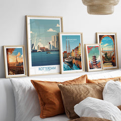 Framed travel posters of Rotterdam, Paris, Copenhagen, Tokyo, and Barcelona above a bed