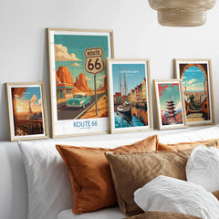 Framed travel art prints of Route 66, Paris, Copenhagen, Tokyo, and Barcelona above a bed