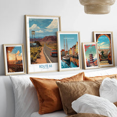 Framed travel posters of Route 66, Paris, Copenhagen, Tokyo, and Barcelona above a bed.