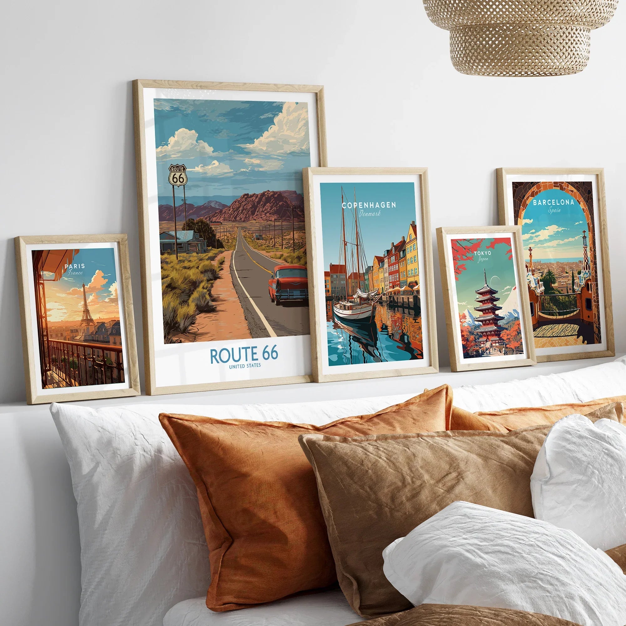 Framed travel posters of Route 66, Paris, Copenhagen, Tokyo, and Barcelona above a bed.