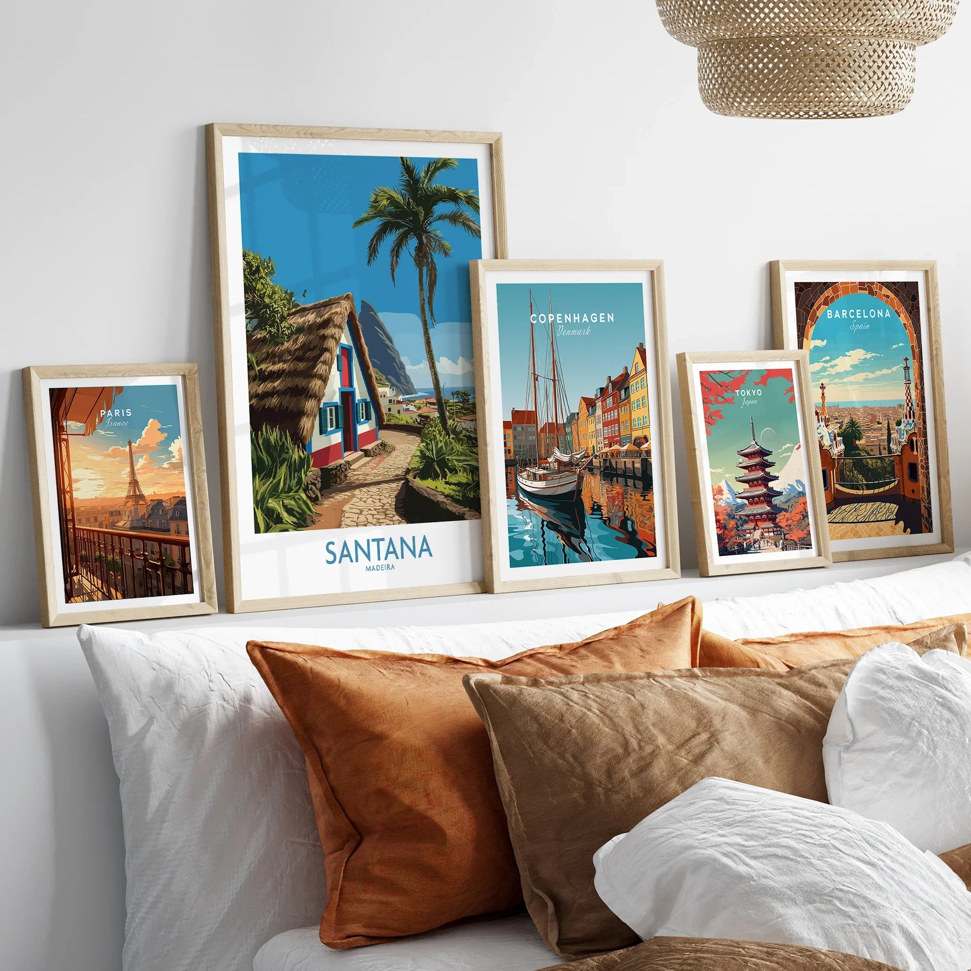 Five framed travel art prints with natural wood frames displayed above a bed