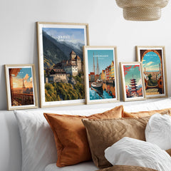 Set of five framed travel art prints featuring city skylines above a bed with natural wood frames