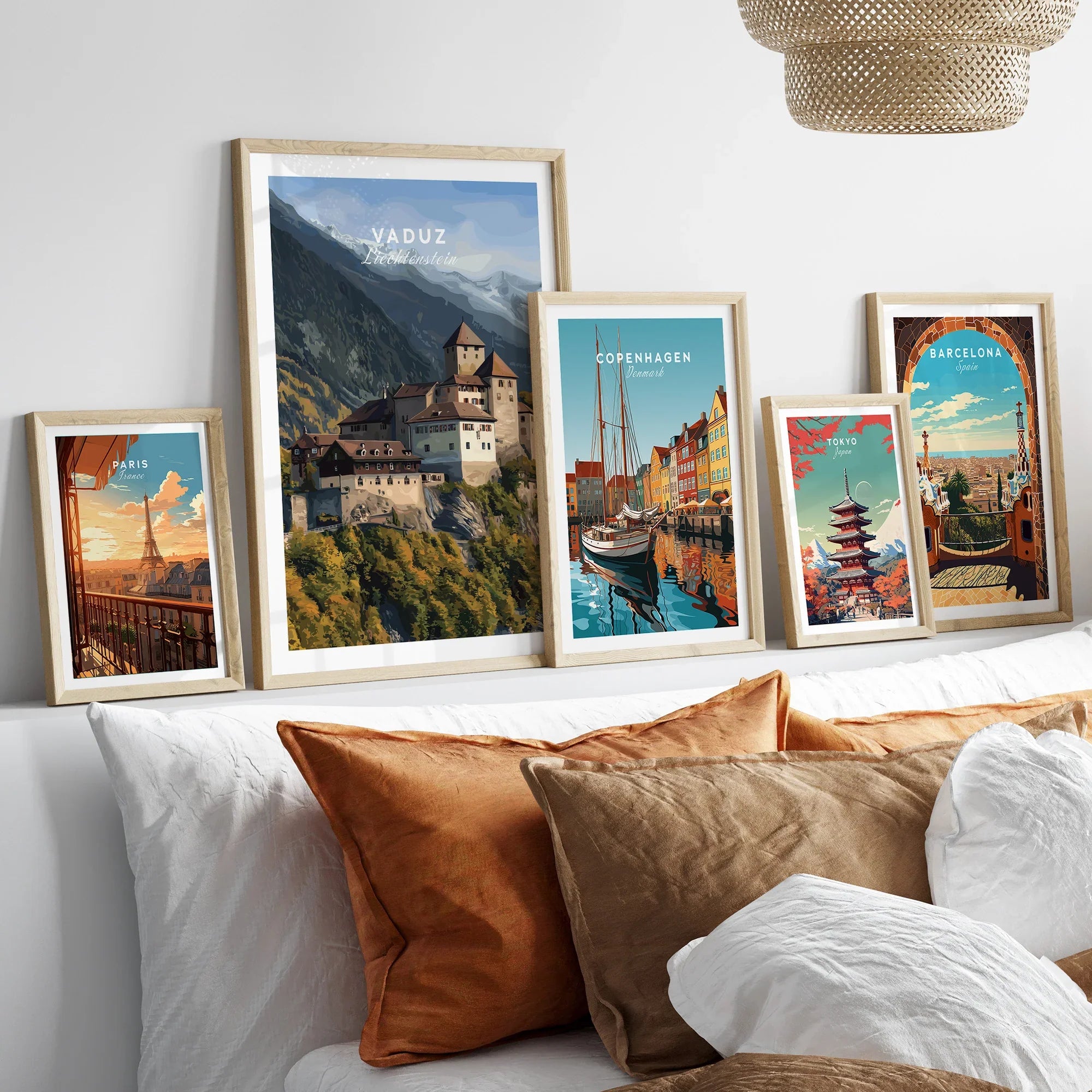 Set of five framed travel art prints featuring city skylines above a bed with natural wood frames