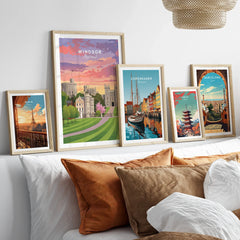 Set of five framed travel art prints with city and landmark illustrations above a bed
