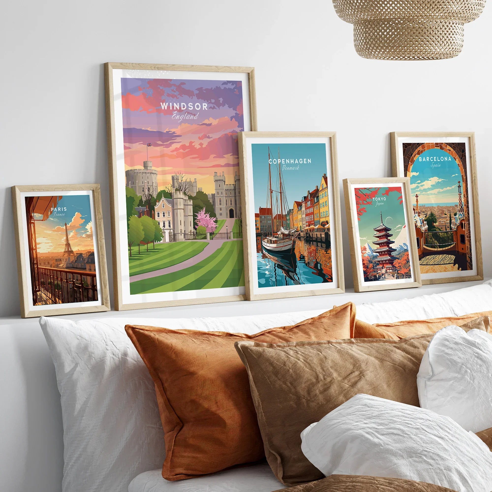 Set of five framed travel art prints with city and landmark illustrations above a bed