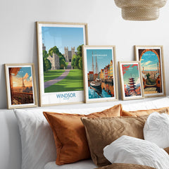 Framed travel posters of Windsor, Copenhagen, Paris, Tokyo, and Barcelona above a bed.