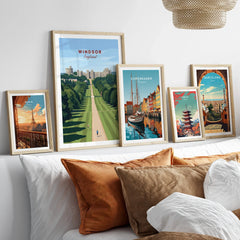 Framed travel posters of Windsor, Copenhagen, Paris, Tokyo, and Barcelona above a bed.