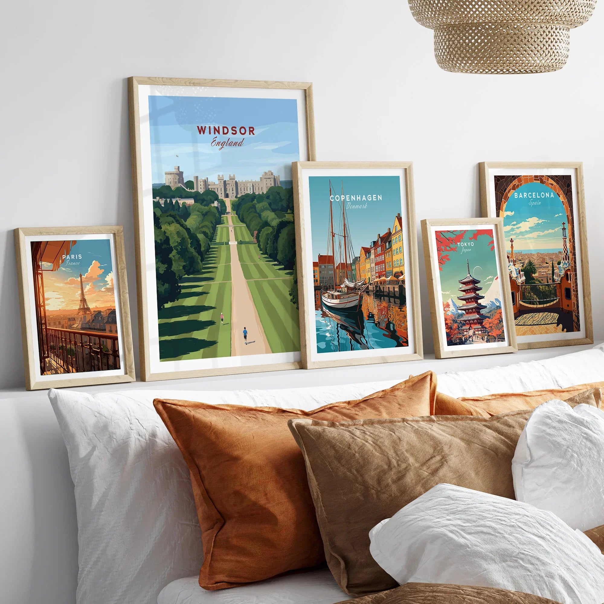 Framed travel posters of Windsor, Copenhagen, Paris, Tokyo, and Barcelona above a bed.