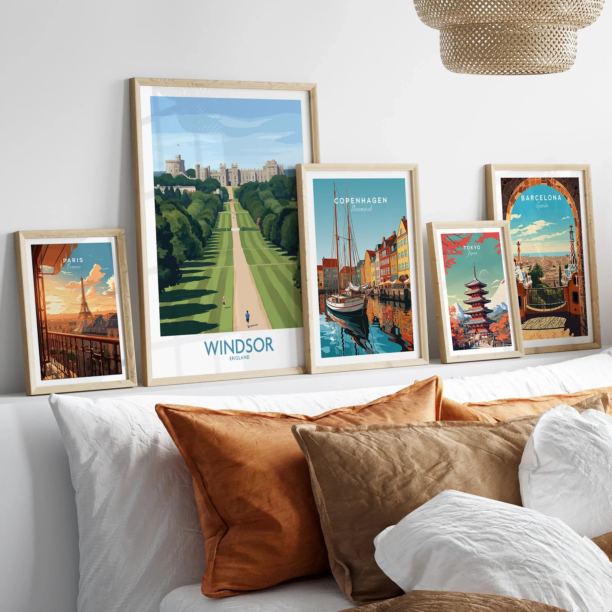 Five framed travel posters featuring Windsor, Paris, Copenhagen, Tokyo, and Barcelona above a bed.