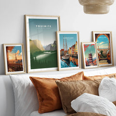 Five framed travel art prints of Paris, Yosemite, Copenhagen, Tokyo, and Barcelona above a bed