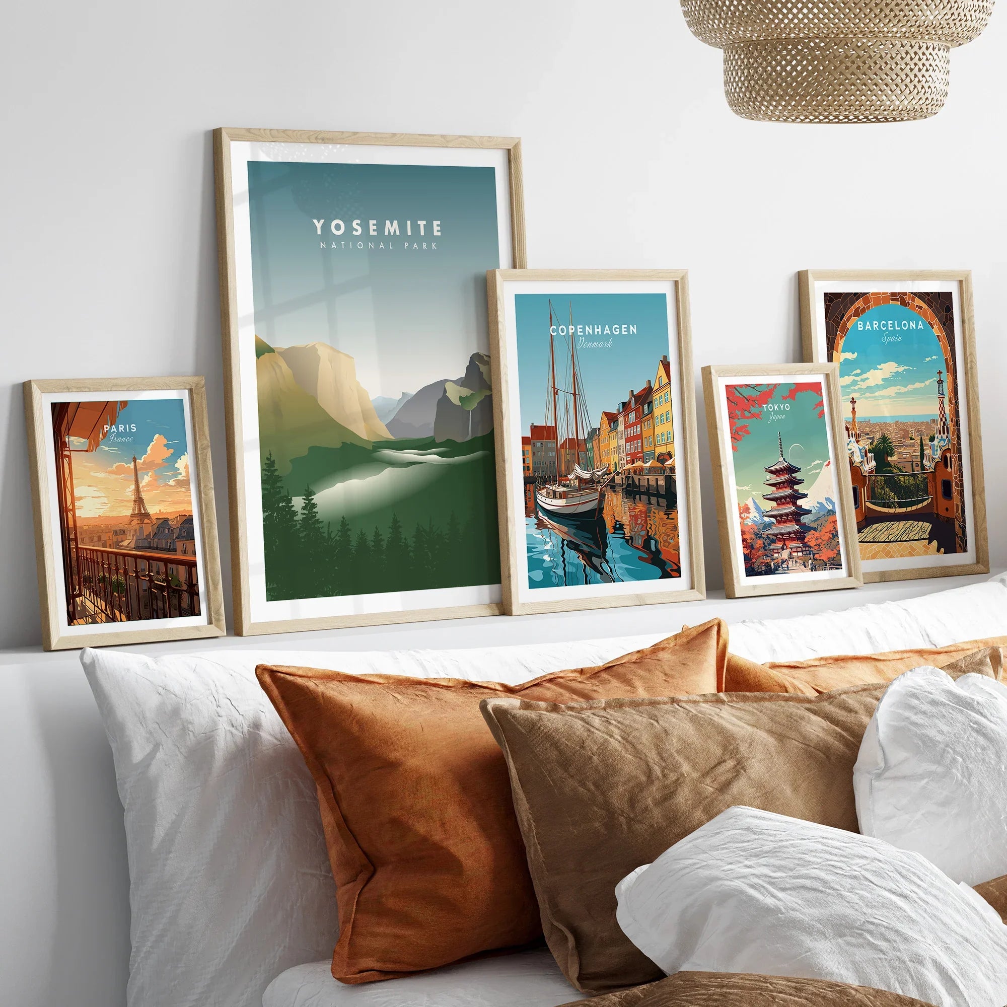 Five framed travel art prints of Paris, Yosemite, Copenhagen, Tokyo, and Barcelona above a bed
