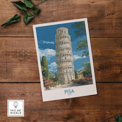 Pisa Italy Bell Tower Travel Wall Art - Historic Tuscany Poster displayed on a wooden table with greenery.