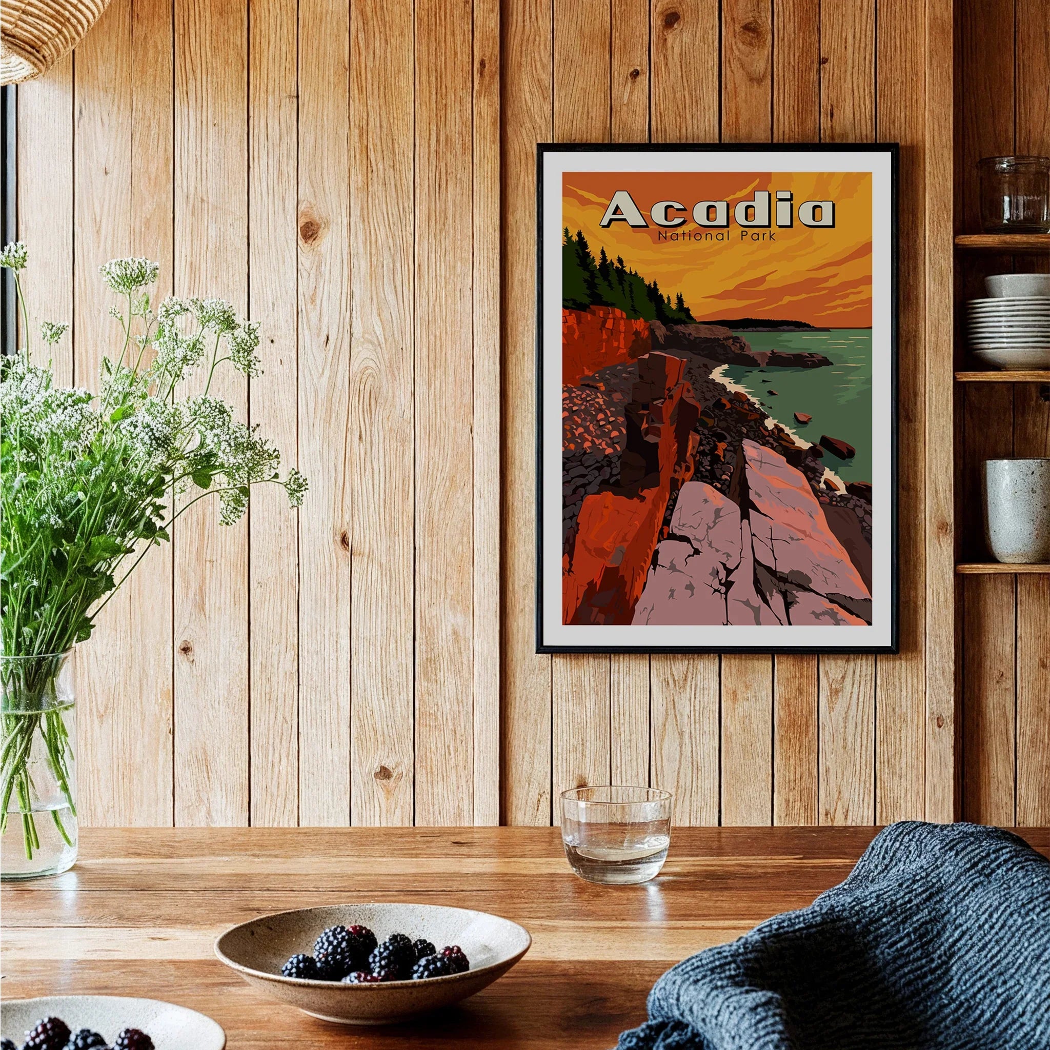 Acadia National Park art print with sunset coastal view in black frame on wood kitchen wall.