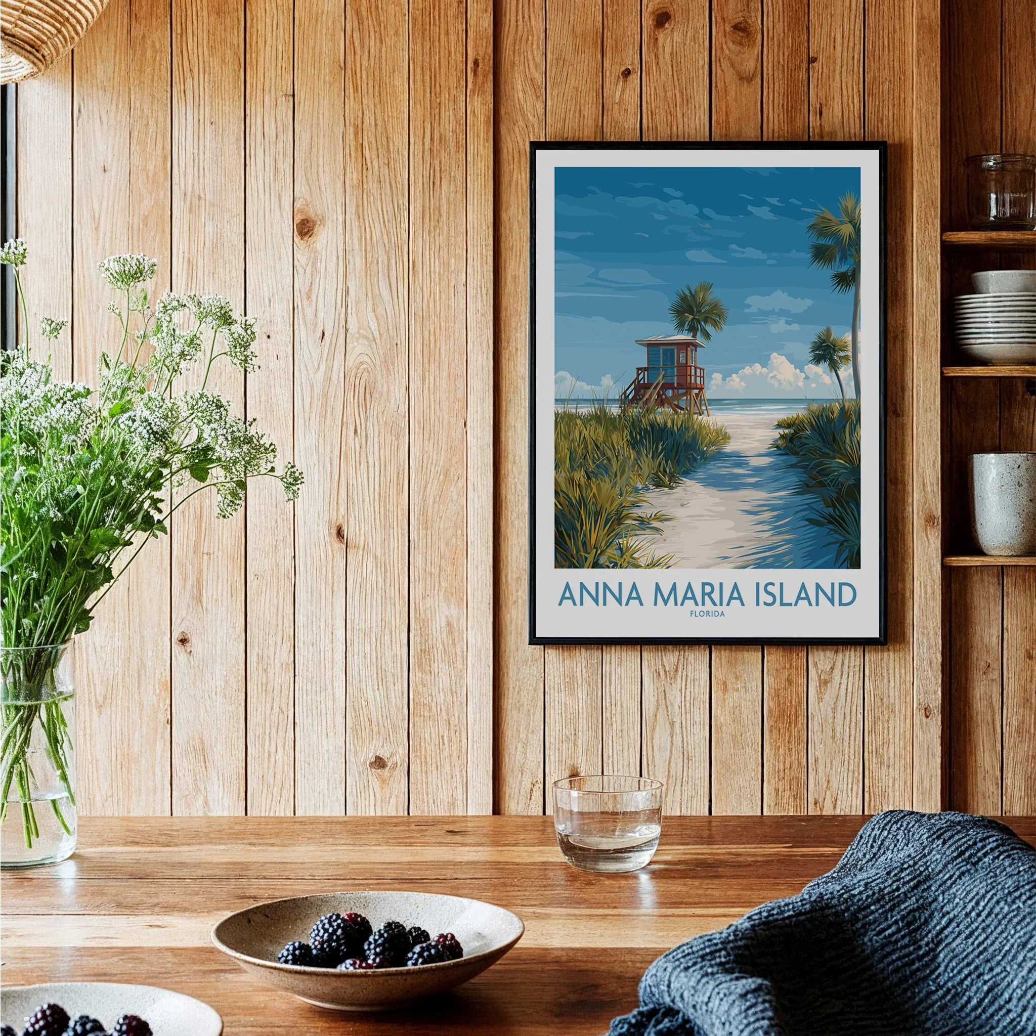 Travel poster print of Anna Maria Island in black frame, displayed in rustic kitchen setting.