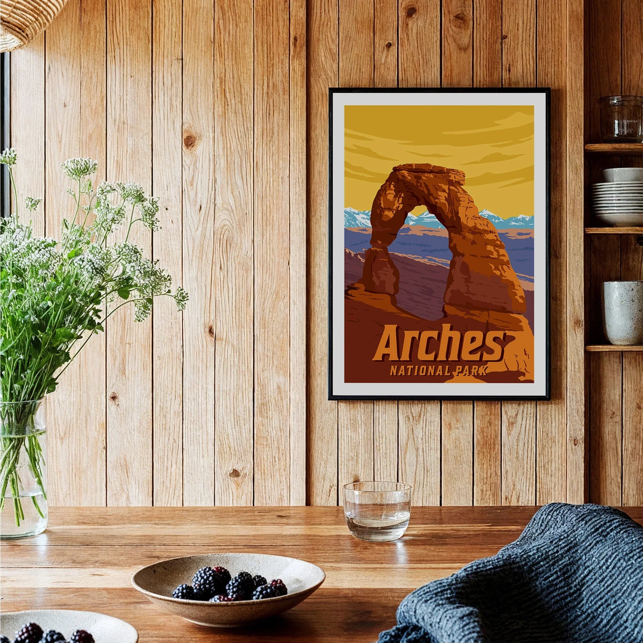 Arches National Park art print in black frame on wooden kitchen wall with berries and flowers
