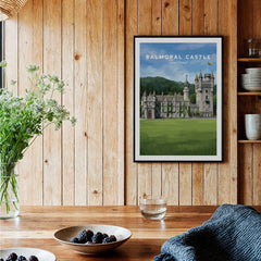 Framed Balmoral Castle art print hanging in rustic kitchen with wood panel walls and table.