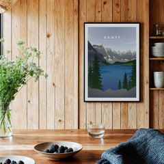 Banff National Park art print in black frame hung in a rustic kitchen with wood walls.