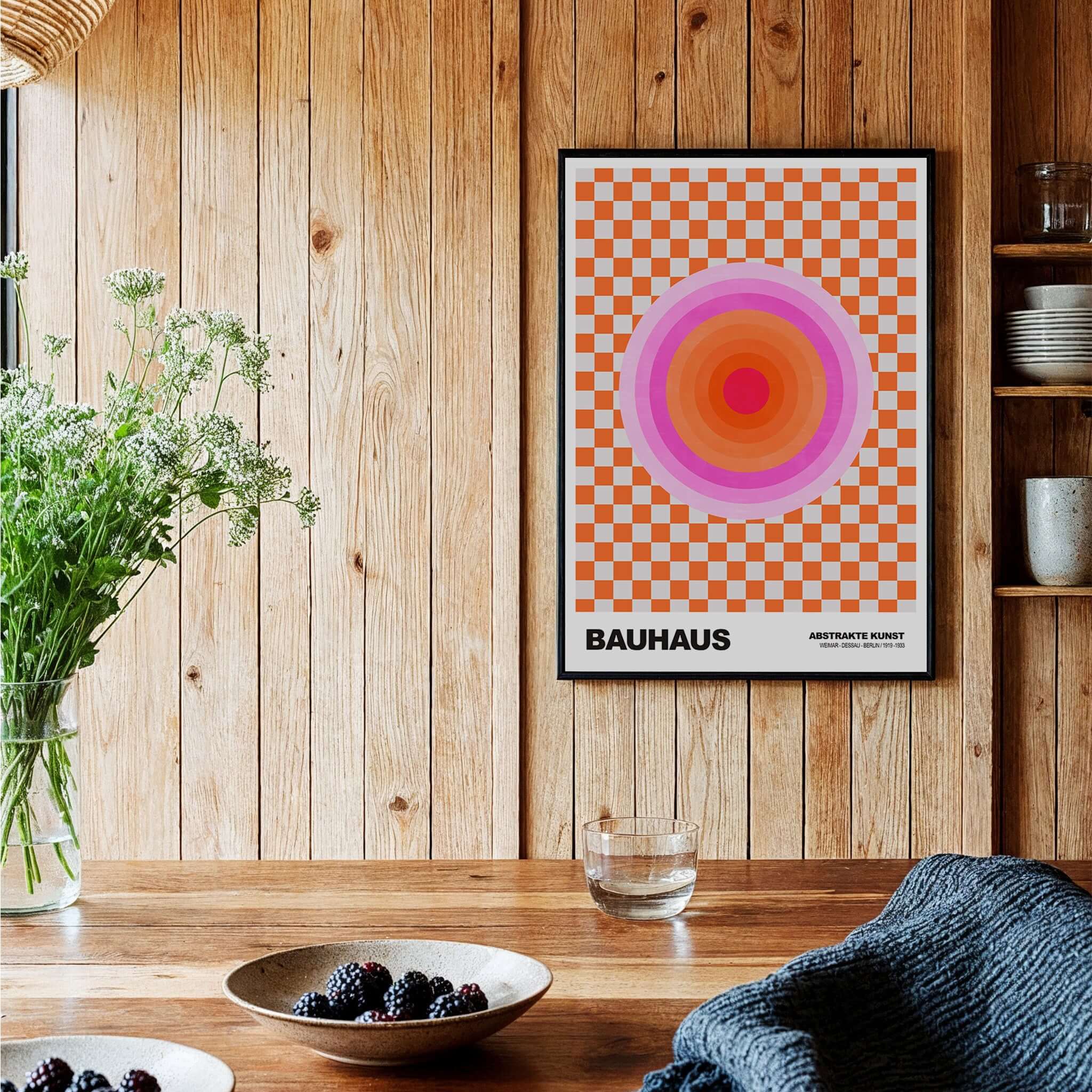 Bauhaus Exhibition Prints - Pink Circles Poster Orange Checkerboard Art framed on a wooden wall with decorative plants.