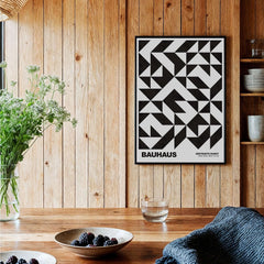 Bauhaus Exhibition Prints - Geometric Triangle Pattern Poster Black White Abstract hanging on a wooden wall with decorated table.