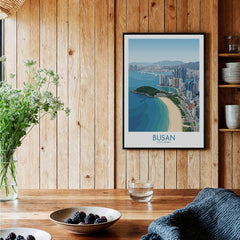 Framed Busan travel poster art print on wooden kitchen wall with beach and city skyline design