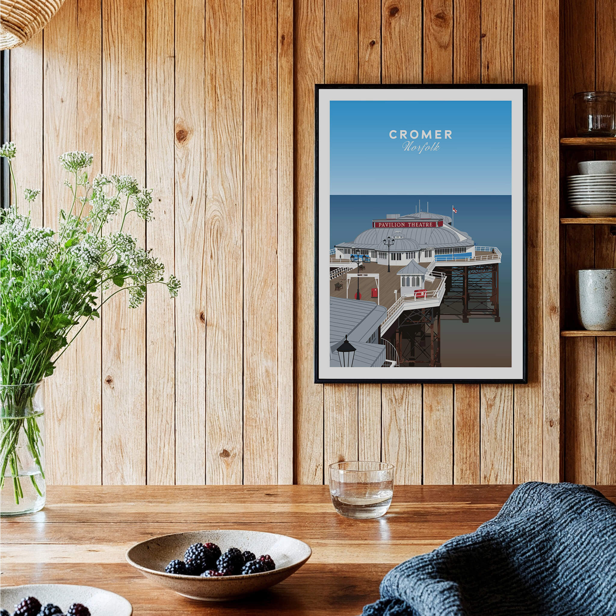 Cromer Travel Poster – Norfolk Pier & Pavilion Theatre Landmark Art displayed on a wooden wall with plants and table.