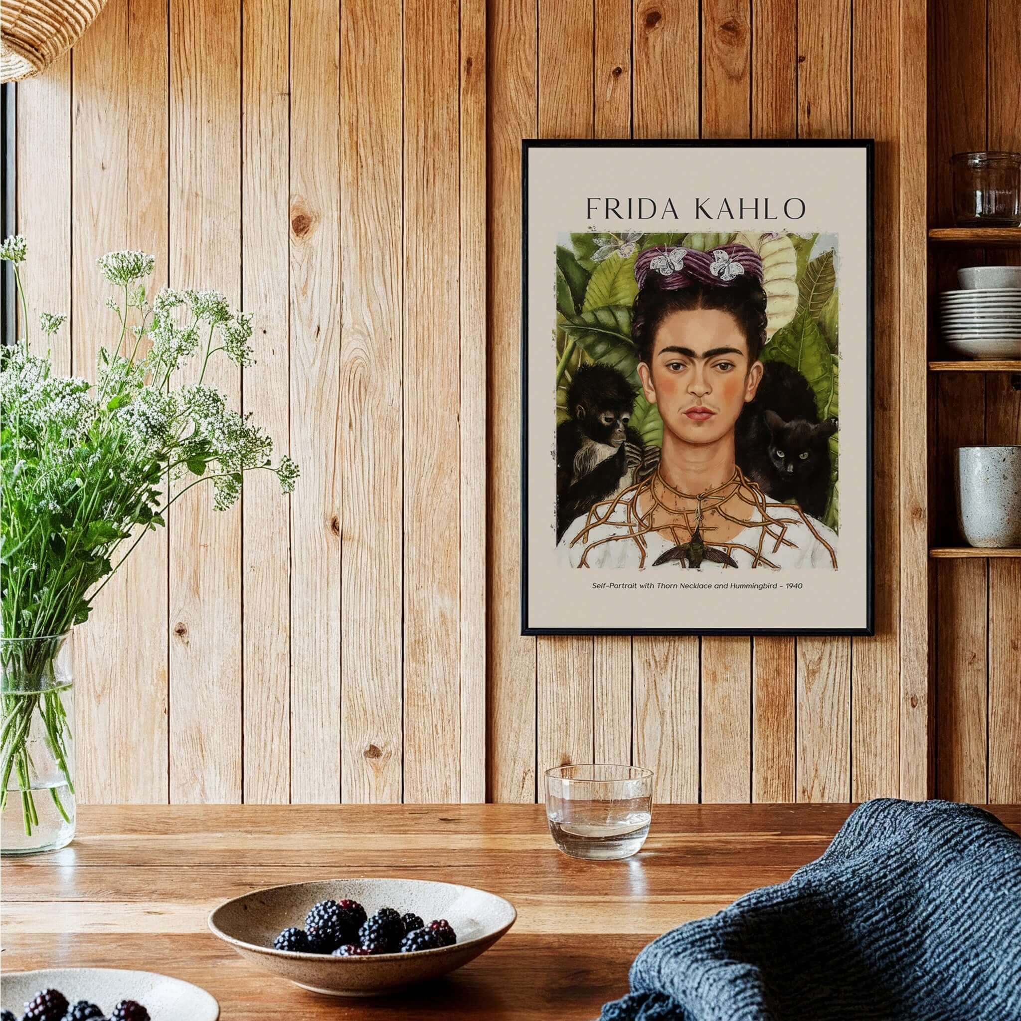 Frida Kahlo Self Portrait with Thorn Necklace and Hummingbird Print displayed on a wooden wall with plants and decor.