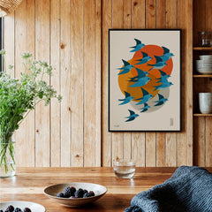 Modern kitchen art print of blue birds with orange sun, framed on wood wall, cozy decor
