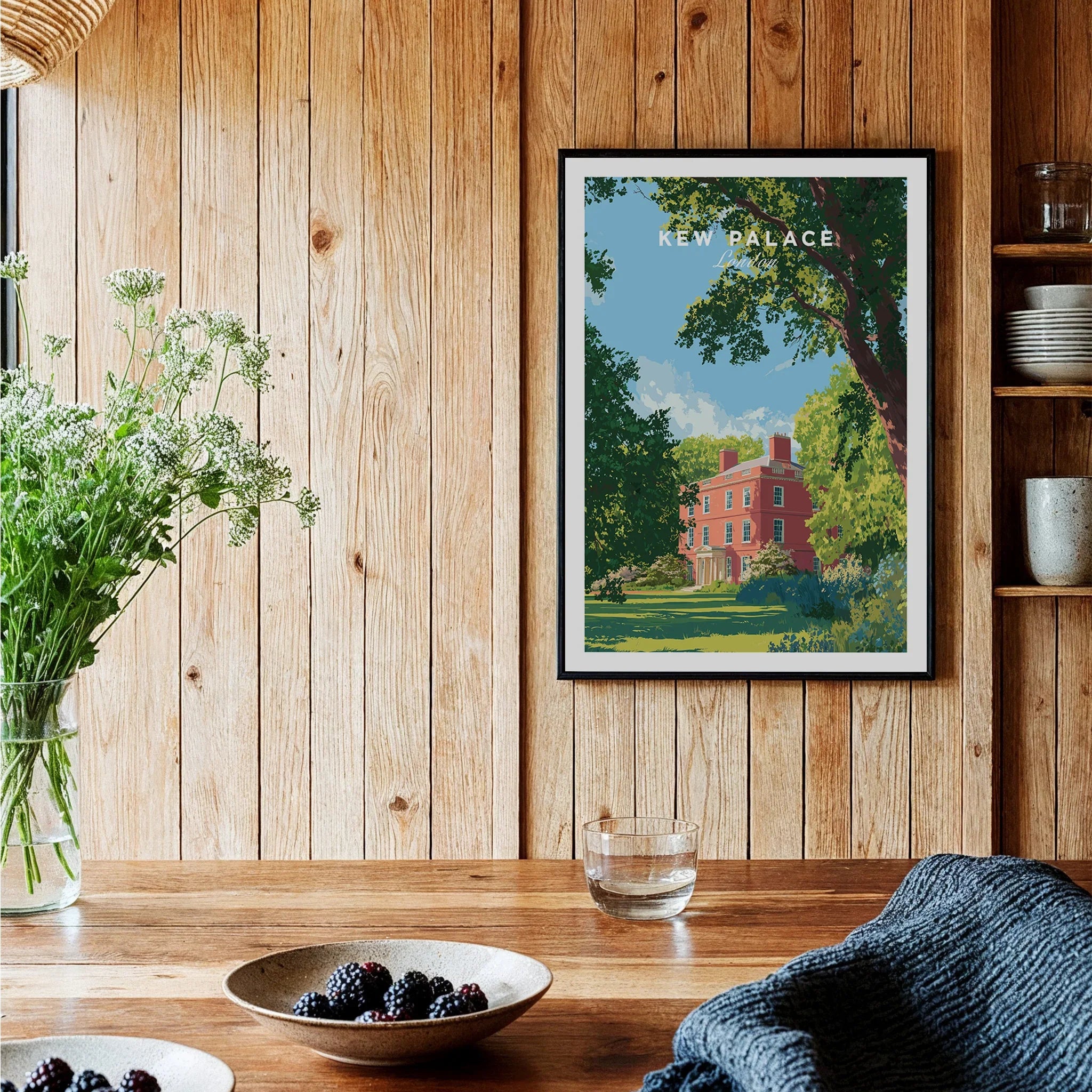 Kew Palace art print in black frame on rustic wood kitchen wall, with bowls of berries and wildflowers