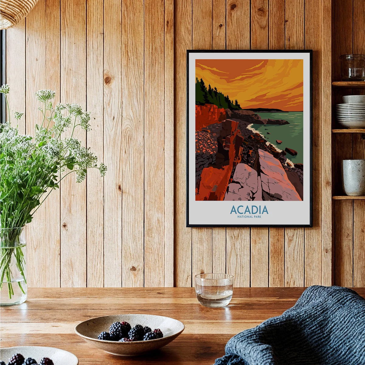 Acadia National Park poster framed on rustic kitchen wall with wood paneling and bowls of berries.