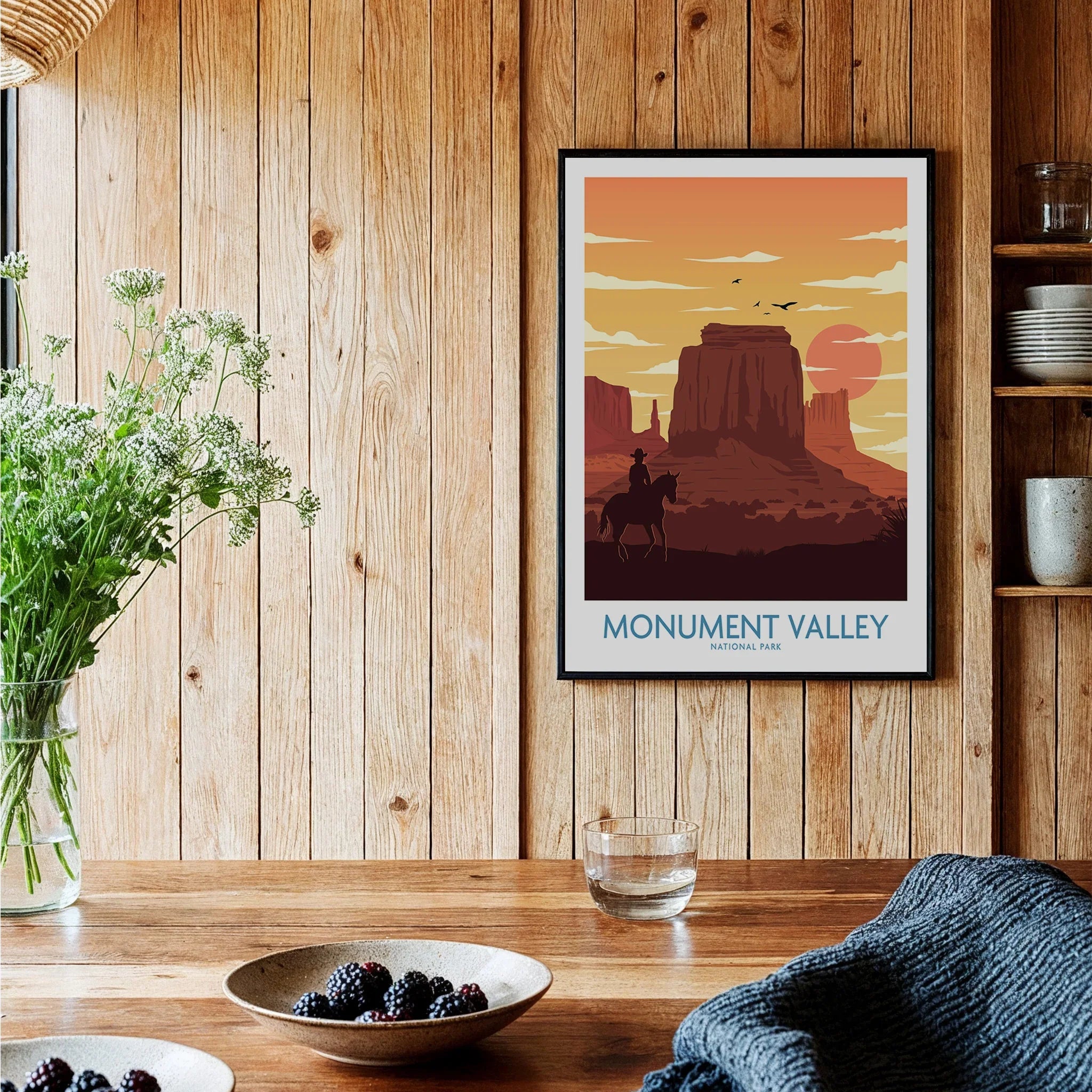 Framed Monument Valley National Park art print on rustic wood kitchen wall, with sun and mesas.