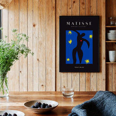 Matisse Art Prints - Icarus Black Figure with Stars Poster displayed in a modern interior setting with wooden accents.
