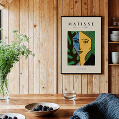 Matisse Art Prints - Split Face Blue Yellow Portrait Poster hanging on wooden wall with foliage and table decor.