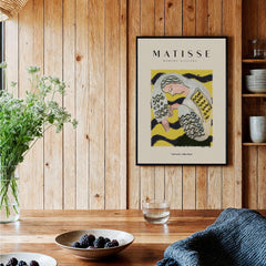 Matisse Art Prints - Resting Woman Patterned Blouse Yellow displayed on wooden wall, surrounded by plants and tableware.