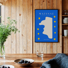 Matisse Art Prints -  Blue Abstract Profile with Yellow Dots Poster displayed on a wooden wall with plants and table.
