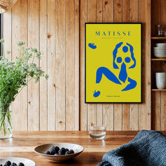 Matisse Art Prints - Blue Nude Abstract Figure Yellow Poster on a wooden wall with plants and table decor.