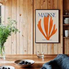 Matisse Papiers Découpés Orange Abstract Botanical Cut Out Art Print displayed on wooden wall with plants and table decor.