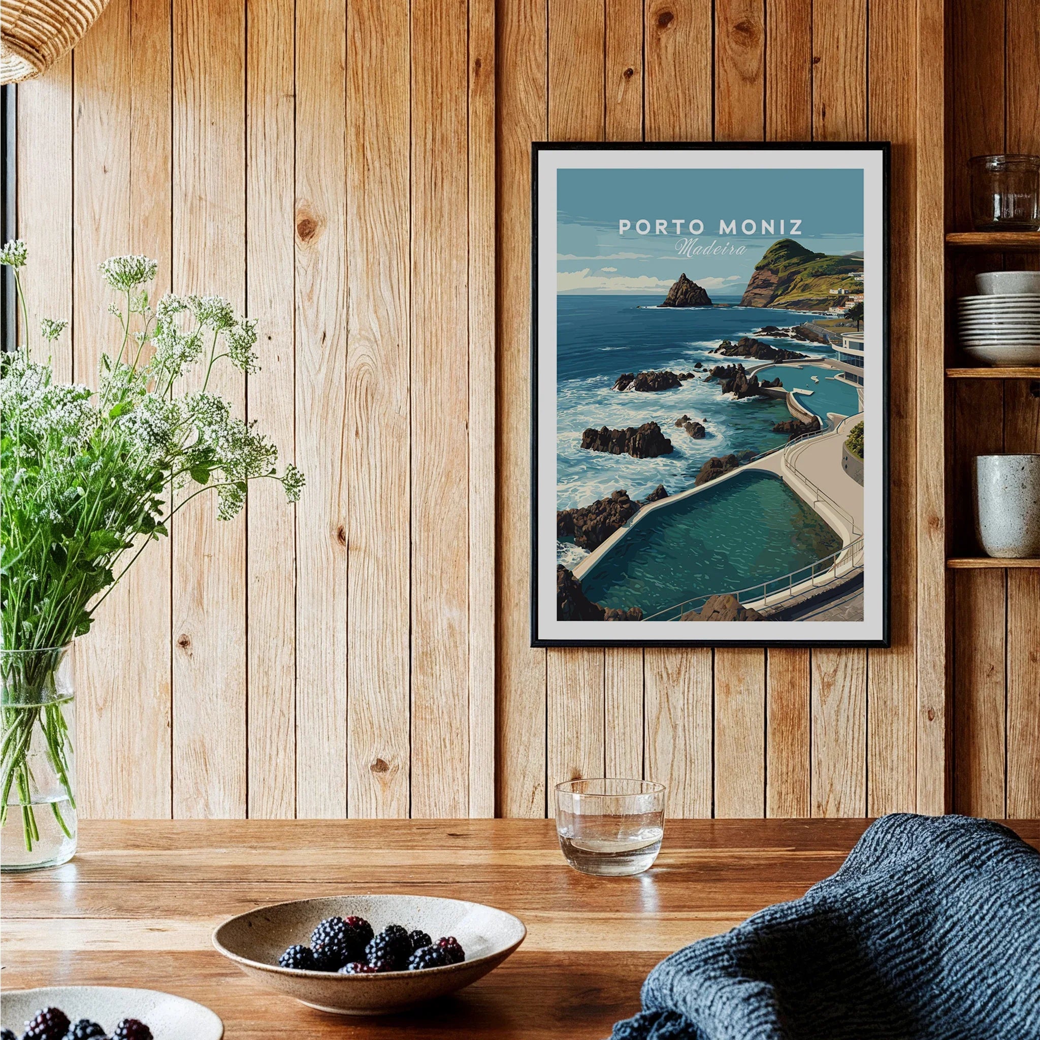 Framed Porto Moniz Madeira travel poster on wood kitchen wall with bowls of berries and flowers