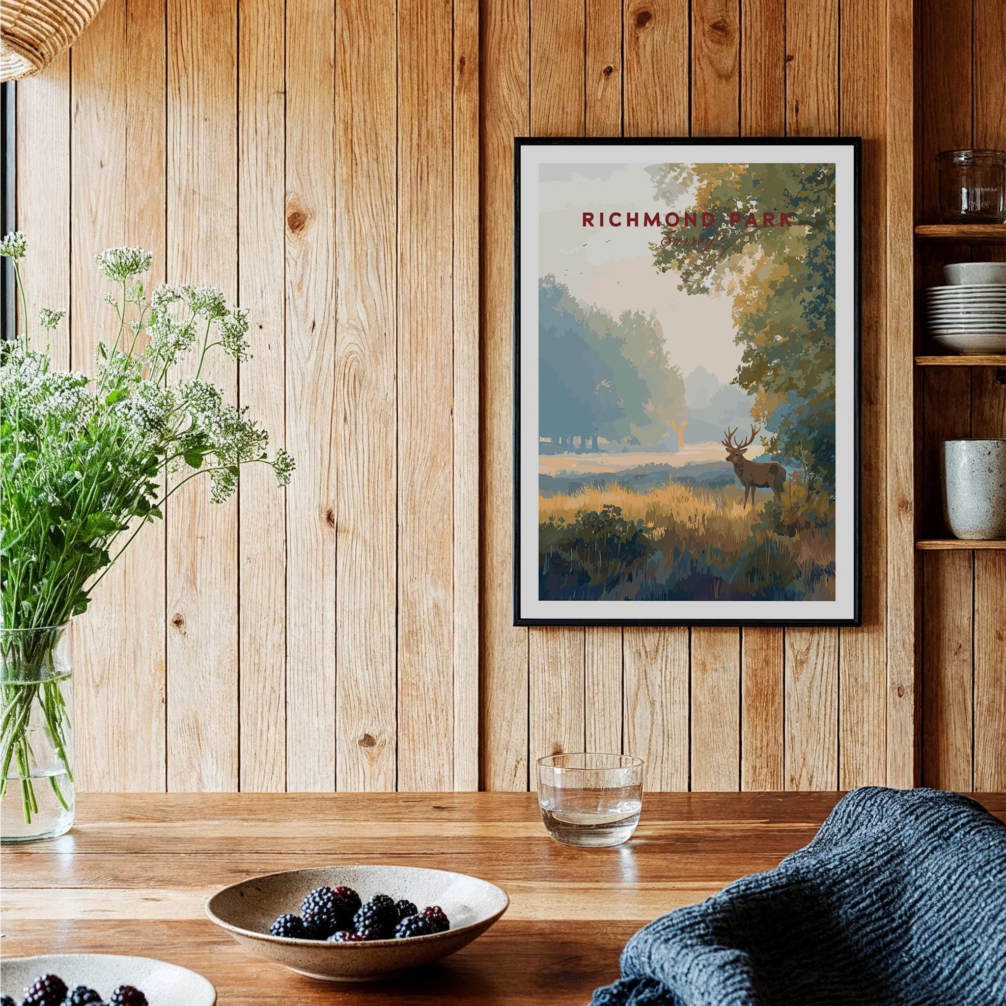 Richmond Park art print in black frame hanging in rustic kitchen with wooden walls and fresh berries on table.