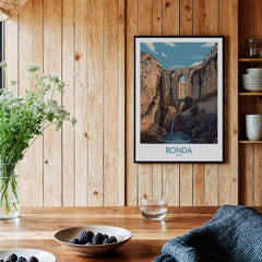 Ronda Spain Poster | Dramatic Andalusian Mountain Bridge Canvas Print displayed in a wooden interior with plants and decor.
