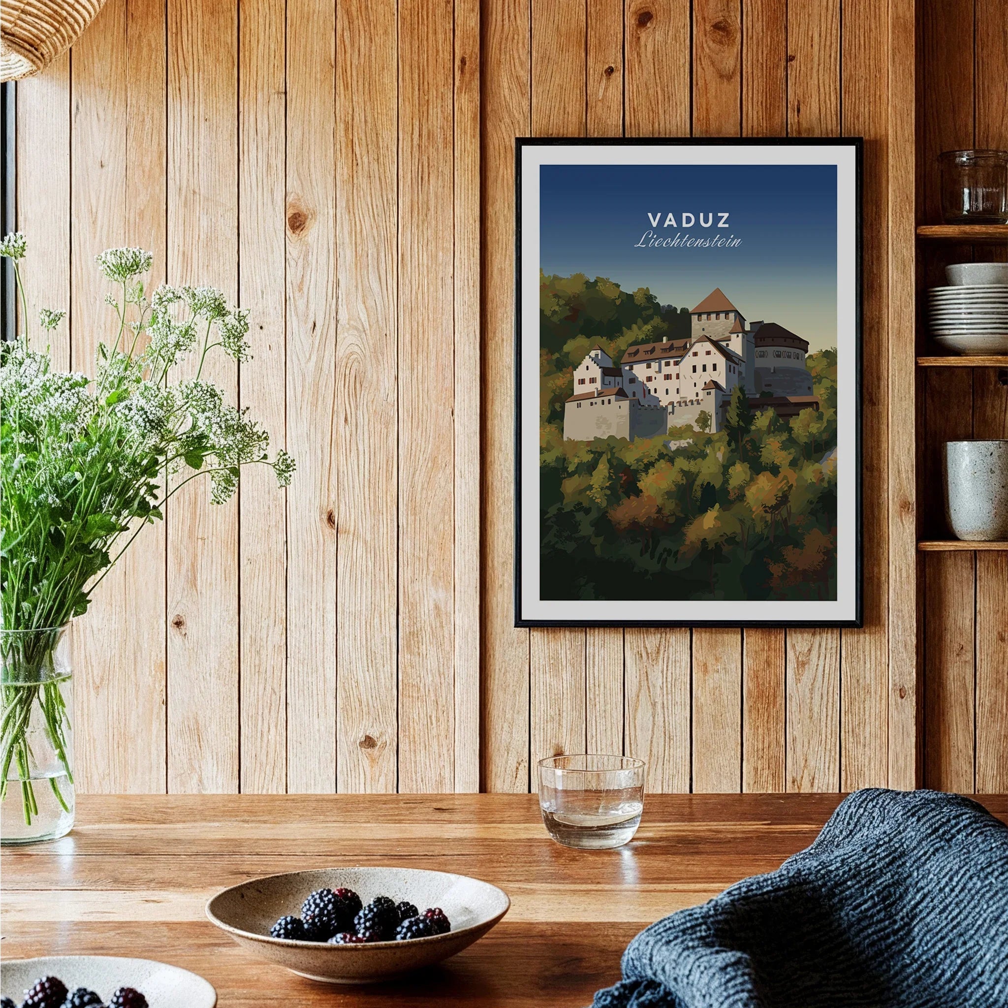 Framed Vaduz Liechtenstein travel poster on wooden kitchen wall, rustic decor, berries on table.
