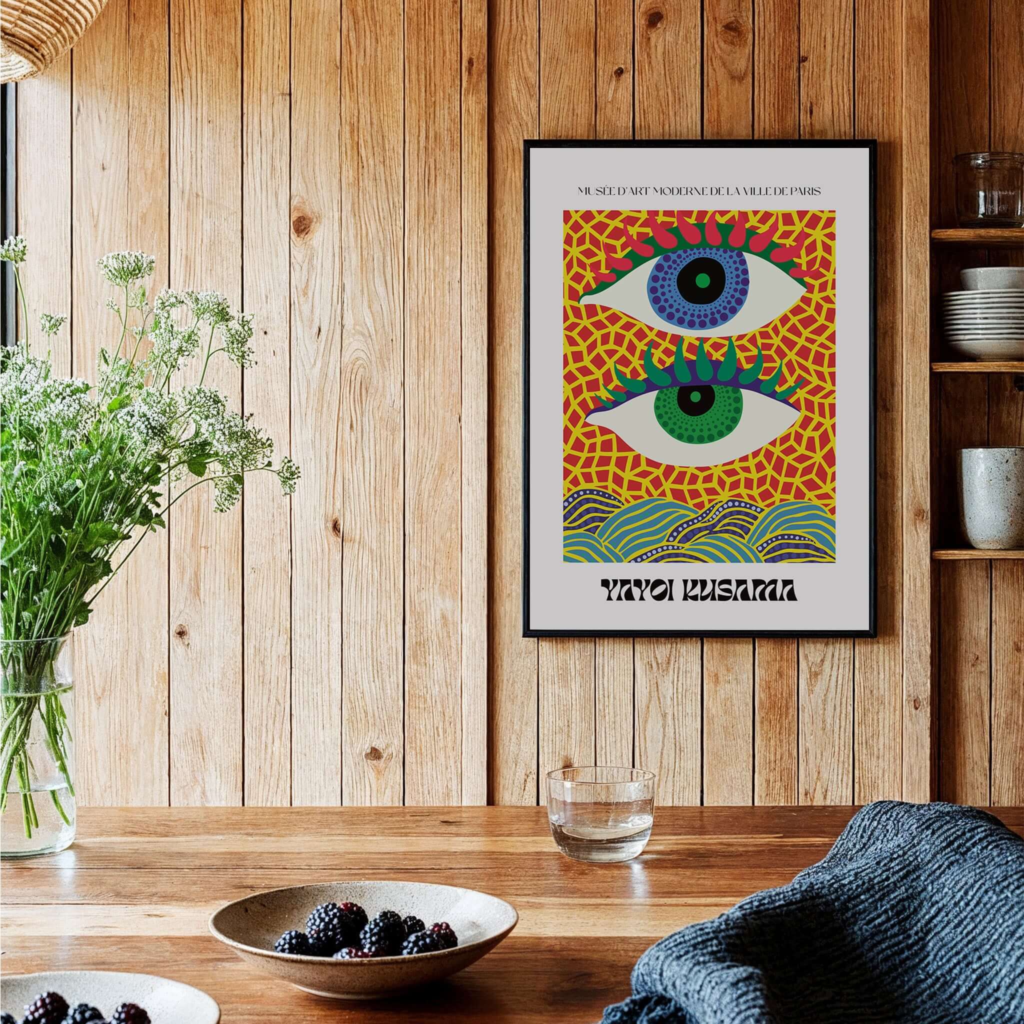 Yayoi Kusama Colorful Eyes Abstract Pattern Contemporary Art Print Paris Poster displayed on a wooden wall with plants.