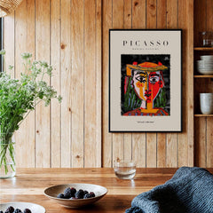 Picasso Woman in Hat Red Yellow Face Portrait Poster Colorful Abstract Artwork Print displayed on wooden wall.