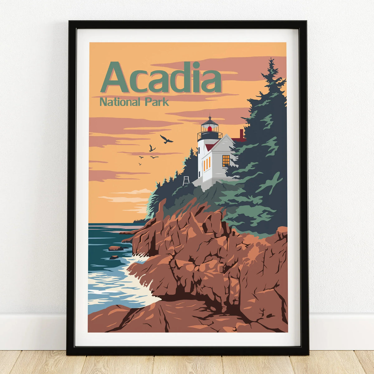 Acadia National Park art print in black frame, featuring coastal cliffs and lighthouse at sunset.