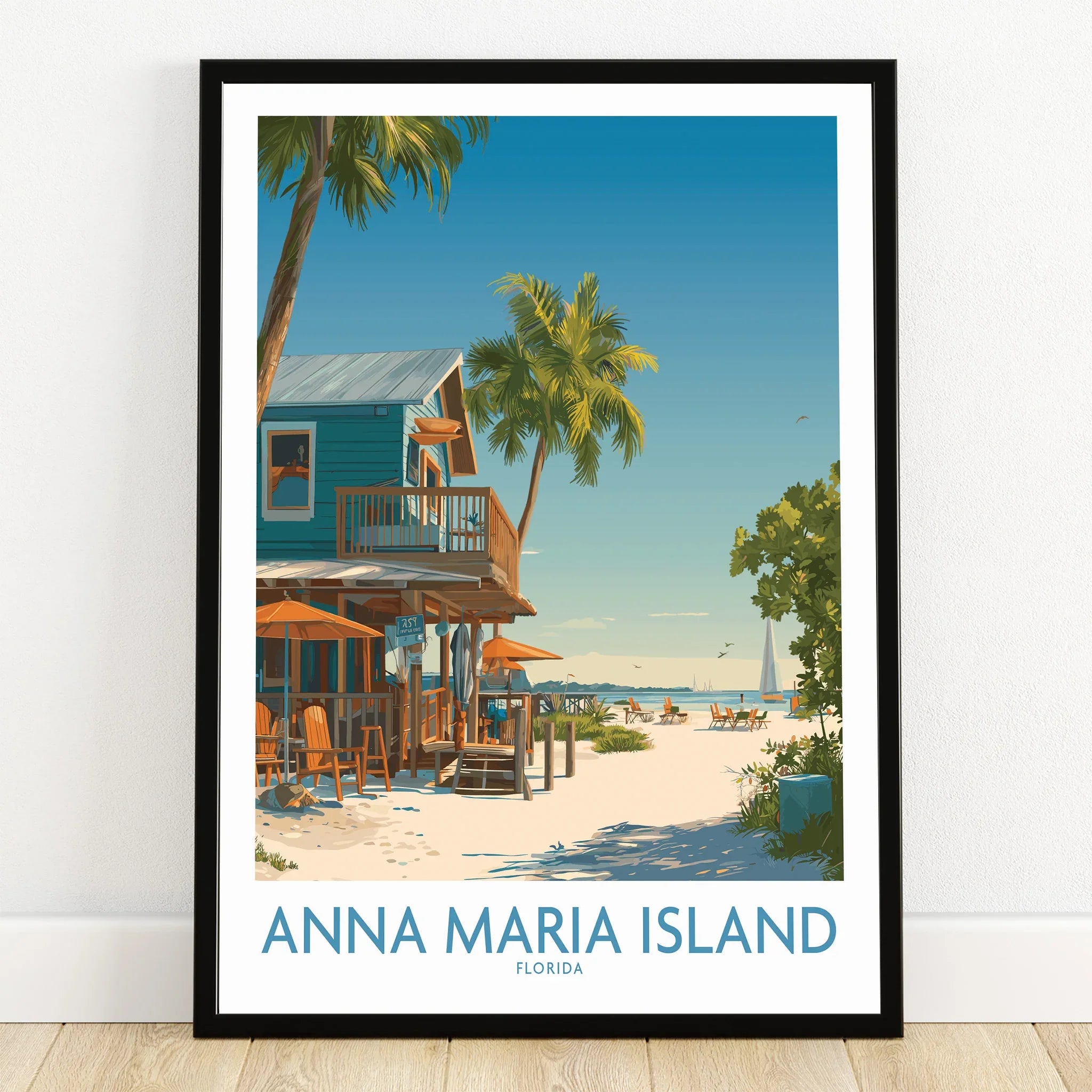 Anna Maria Island Florida art print in black frame on wood floor, featuring tropical beach scene with palm trees, beach house, and ocean view.